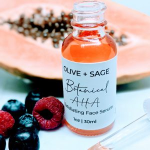 Botanical AHA Face Oil in glass dropper bottle with dropper out, surrounded by papaya and raspberries for skin exfoliation and hydration.