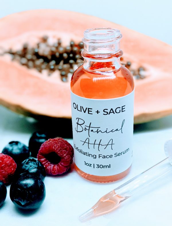 Botanical AHA Face Oil in glass dropper bottle with dropper out, surrounded by papaya and raspberries for skin exfoliation and hydration.