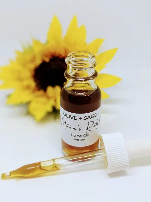 Nature’s Retinol Face Oil bottle with dropper resting beside it and sunflower in background. Plant-based retinol alternative by Olive + Sage.