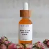 Close-up of Rose Glow Anti-Aging Serum in glass dropper bottle with dried roses around it