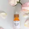 Rose Glow Anti-Aging Serum dropper bottle lying down with pink and white roses around it