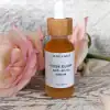 Rose Glow Anti-Aging Serum dropper bottle with a pink rose beside it