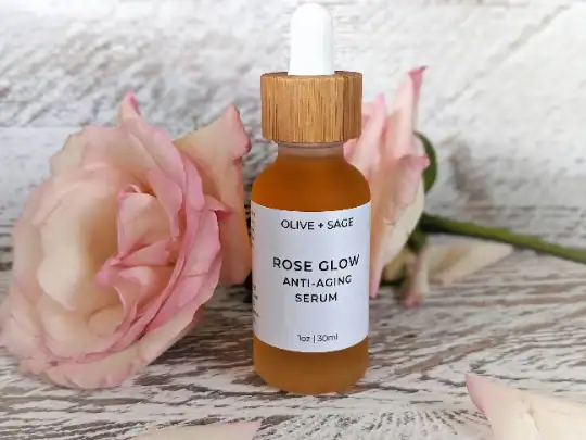 Rose Glow Anti-Aging Serum dropper bottle with a pink rose beside it