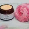 Smooth texture of whipped tallow cream in a glass jar with pink rose beside it.