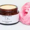 Whipped tallow cream in a glass jar with lid off, accented by a pink rose, showcasing natural ingredients.