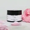 Whipped tallow cream in a glass jar with lid on, pink rose beside it, showcasing natural skincare.