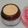 Whipped tallow cream in a glass jar showing texture and color with pink rose beside it.