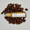 Organic Coffee Under Eye Oil with the top off from a side view on coffee beans