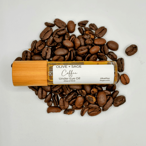 Organic Coffee Under Eye Oil with the top on, placed on coffee beans