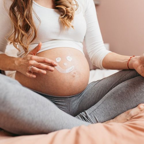 Raw botanical belly skincare balm for pregnancy with smiley face made of cream