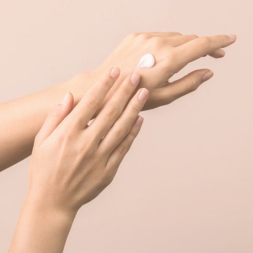 Hands applying raw botanical body skincare cream for soft, nourished skin
