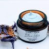 Top-down view of Blue Lotus Face Cream showing whipped botanical texture and soft blue lotus petal accents.
