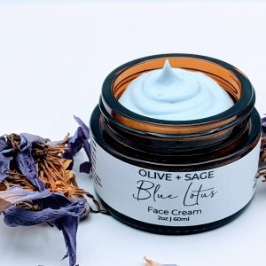 Top-down view of Blue Lotus Face Cream showing whipped botanical texture and soft blue lotus petal accents.