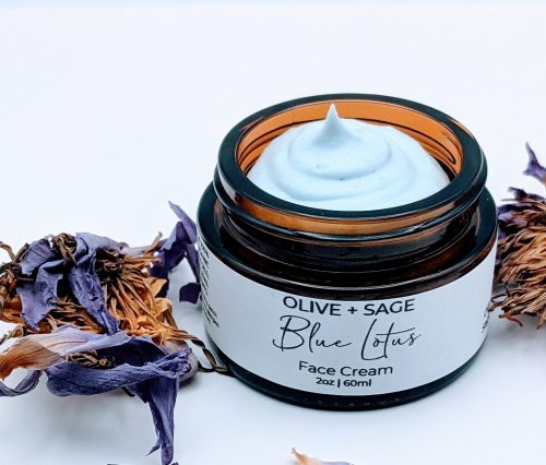 Top-down view of Blue Lotus Face Cream showing whipped botanical texture and soft blue lotus petal accents.