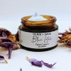 Blue Lotus Face Cream 2 oz glass jar with cream visible, surrounded by fresh blue lotus petals. Calming botanical moisturizer for sensitive skin.