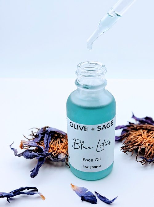 Blue Lotus Face Oil dropper dripping golden facial oil with blue lotus flowers in background, soothing skincare for redness-prone skin