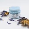 Another view of the Blue Lotus Face Scrub open jar with lotus flower beside it