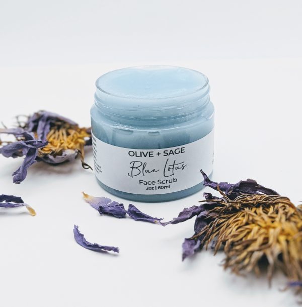 Another view of the Blue Lotus Face Scrub open jar with lotus flower beside it