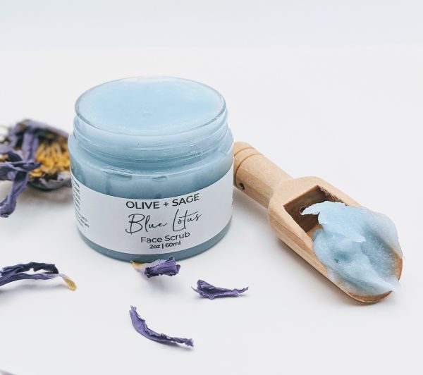 Wooden scoop of Blue Lotus Face Scrub resting in an open jar