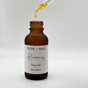 Dropper releasing golden botanical oil into Recovery Face Oil bottle.