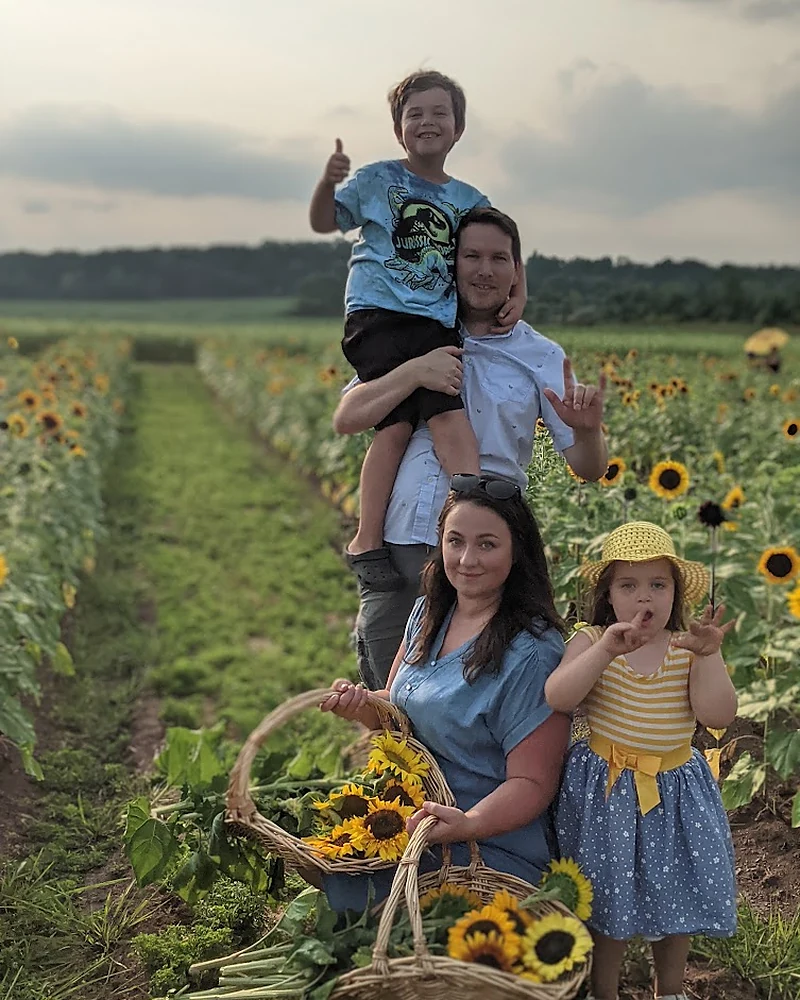 Olive Plus Sage founder with her family in a sunflower field holding baskets of sunflowers
